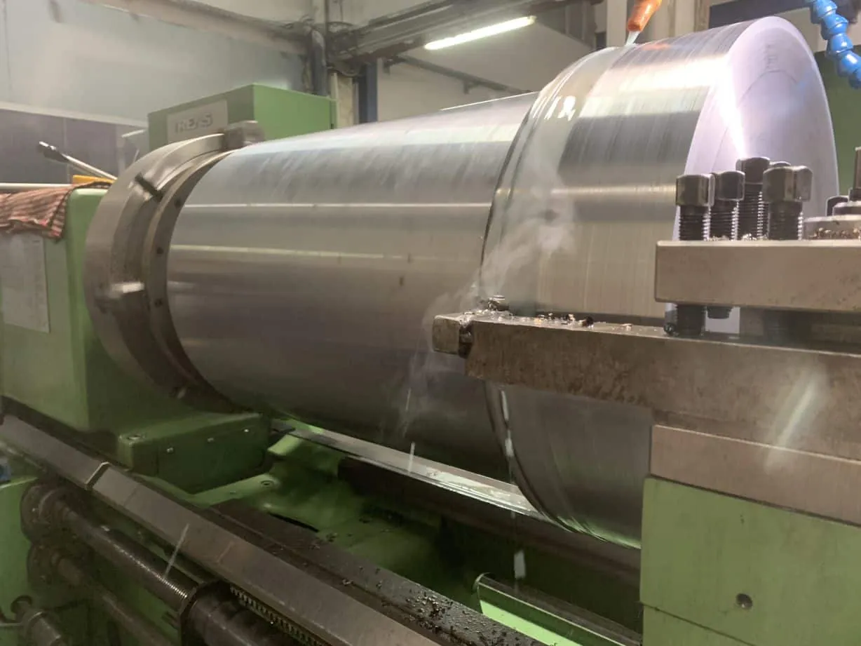 Large diameter steel roller drum being turned on a heavy lathe